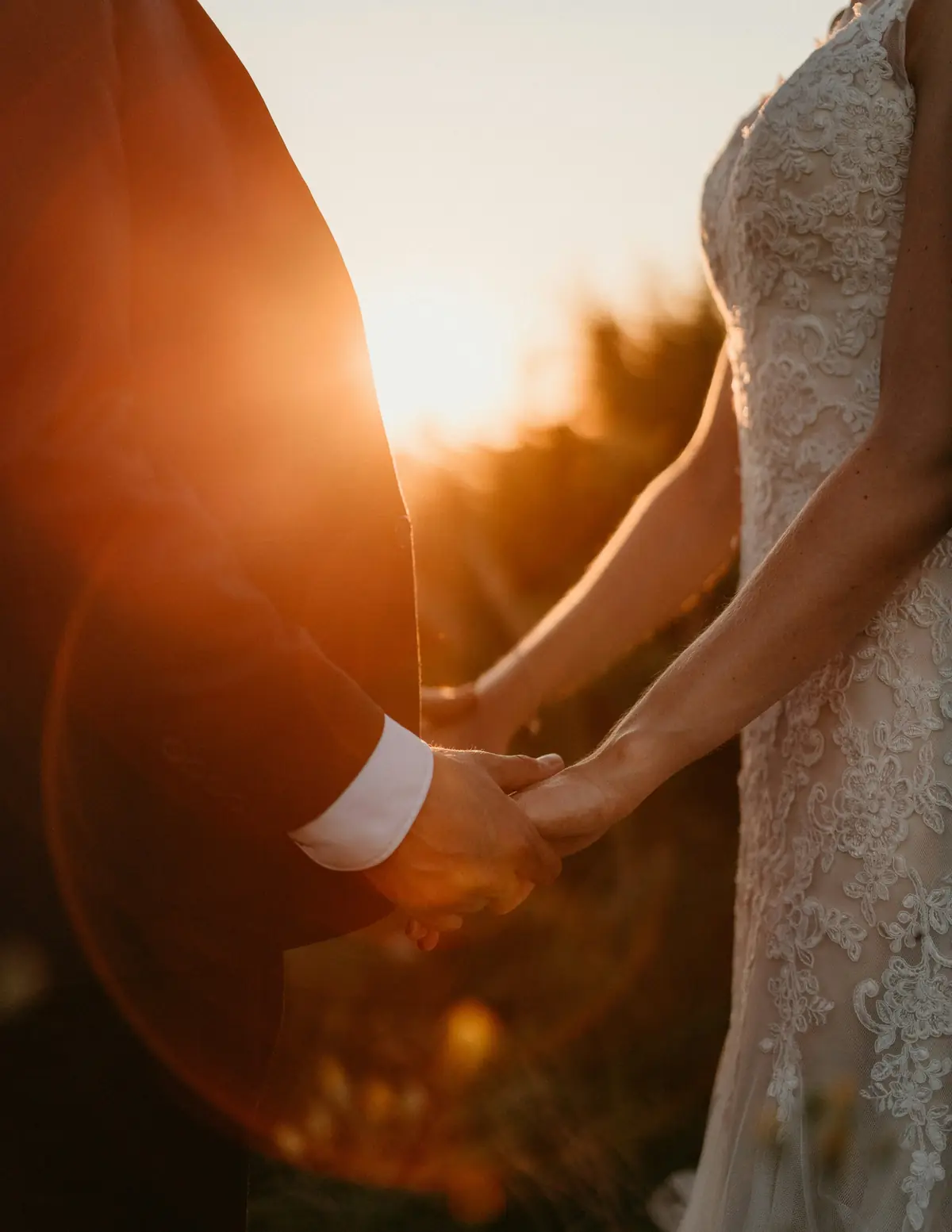 Two hands joined against a low golden sun