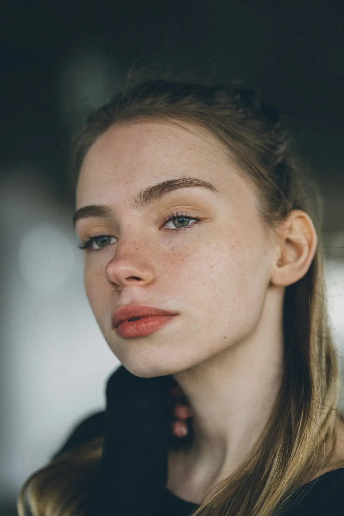 Close portrait of a freckled young woman in soft light