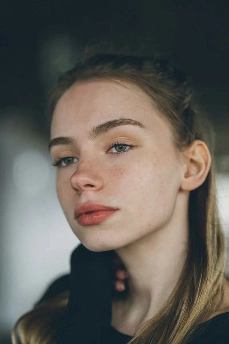 Close portrait of a freckled young woman in soft light
