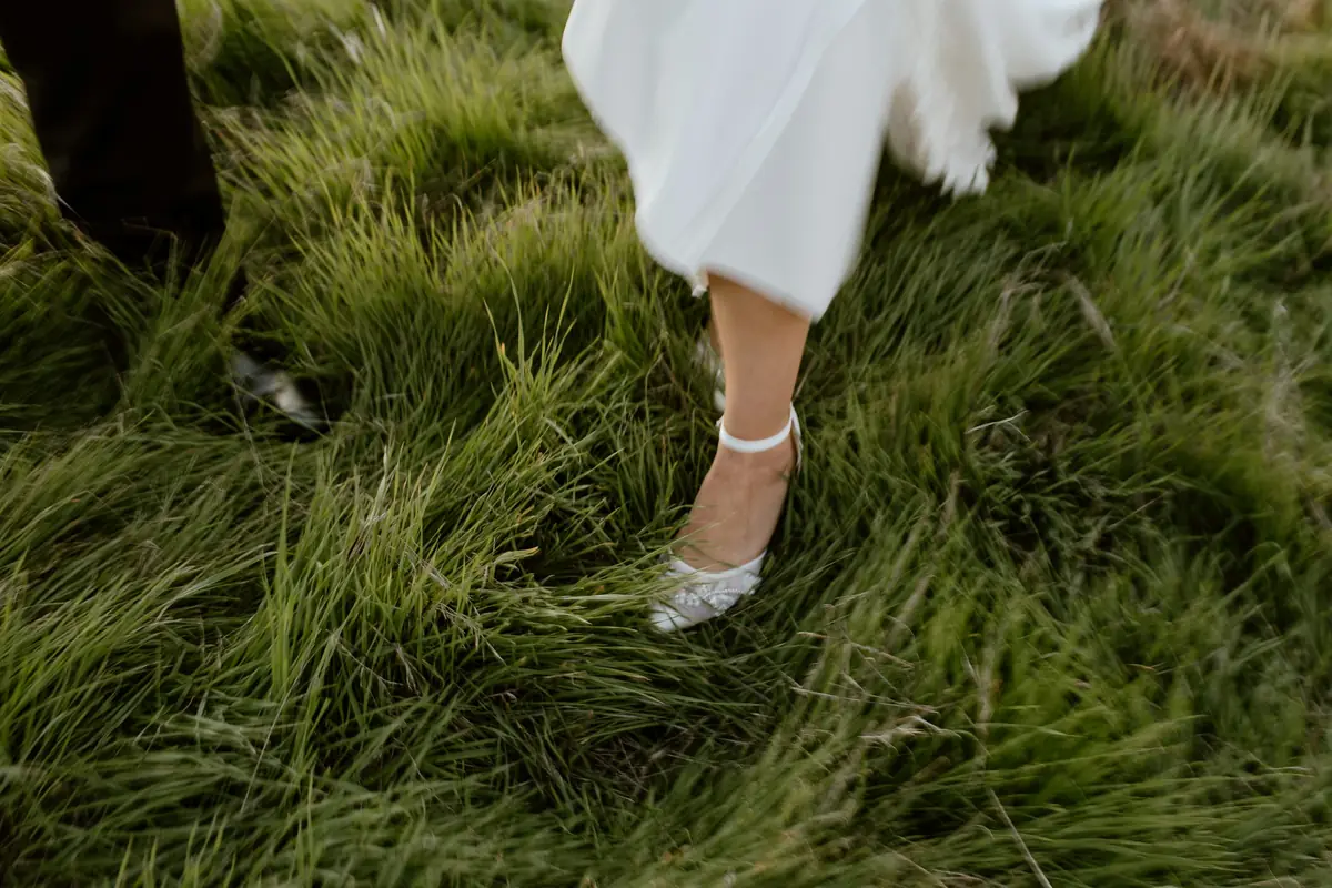 Wedding dress hem and shoe in long grass