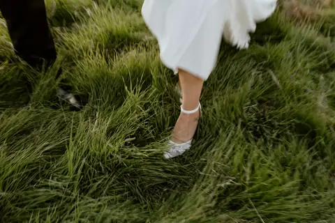 Wedding dress hem and shoe in long grass